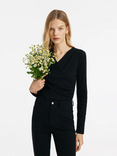 a lady in black v-neck crossover knit top with black skinny jeans